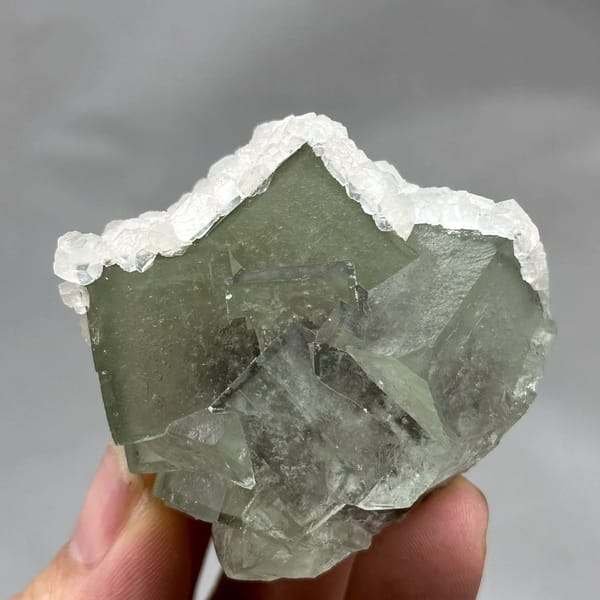 Glassy green fluorite block rimmed with white calcite from Xianghualing, Hunan, China