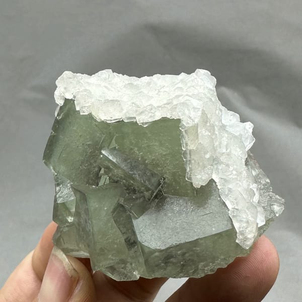 Glassy green fluorite block rimmed with white calcite from Xianghualing, Hunan, China, close-up of the crystal faces