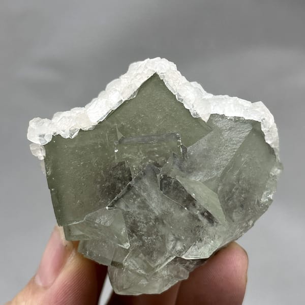 Glassy green fluorite block rimmed with white calcite from Xianghualing, Hunan, China, detail of the matrix contact