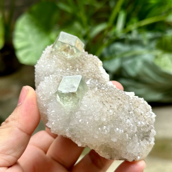 Two transparent green dodecahedral fluorite crystals on white quartz from Fujian, China, close-up of the crystal faces