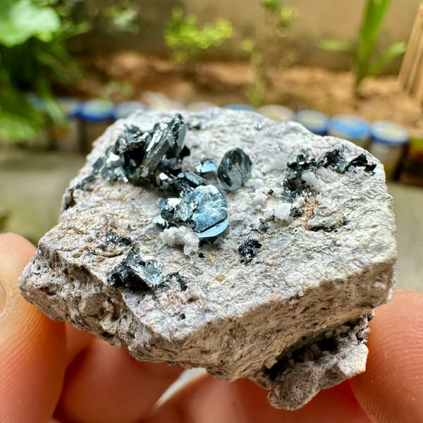 Black hematite rosettes on grey rock from Sichuan, China, held in hand