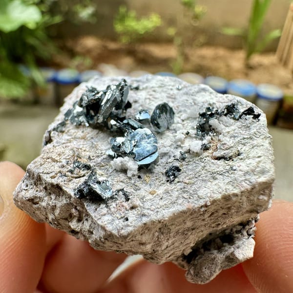 Black hematite rosettes on grey rock from Sichuan, China, detail of the matrix contact