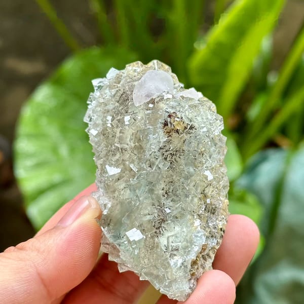 Gemmy pale-green fluorite cubes with calcite from Xianghualing, Hunan, China, held in hand