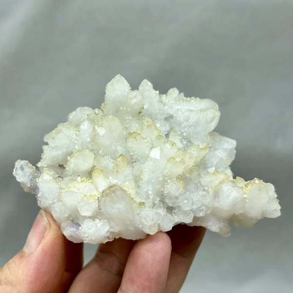 Yellow-skinned quartz cluster with purple fluorite from Fujian, China, held in hand