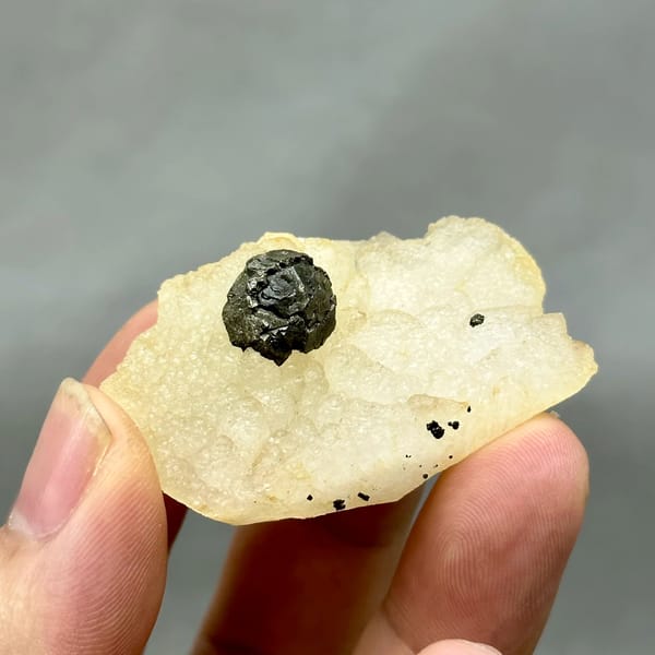 Black botryoidal pyrite ball on cream fluorite from Jiangxi, China, close-up of the crystal faces