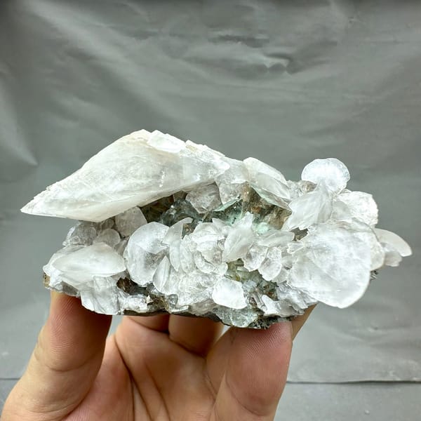 White calcite blades over glassy green fluorite from Xianghualing, Hunan, China, held in hand