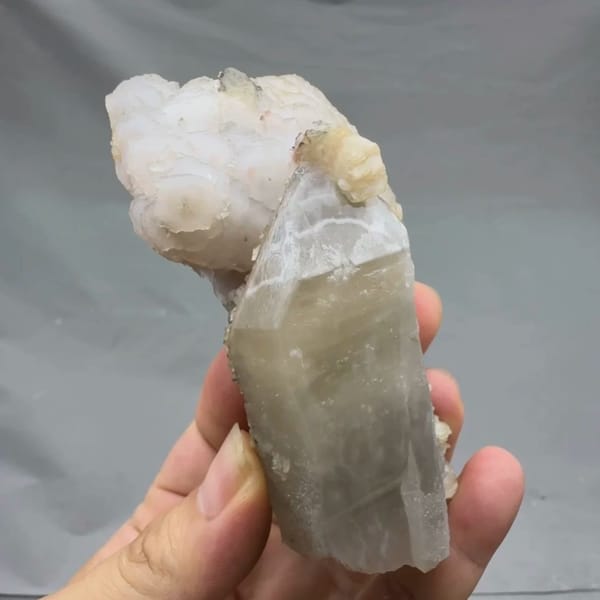Pale quartz prism topped with layered white calcite from Inner Mongolia, China, close-up of the crystal faces