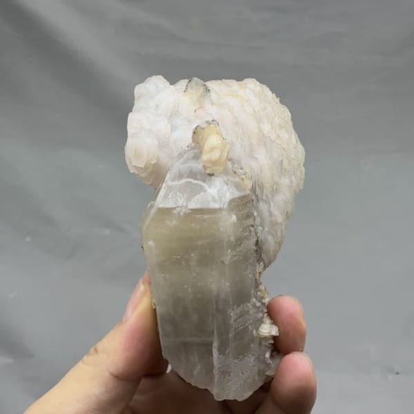 Pale quartz prism topped with layered white calcite from Inner Mongolia, China, detail of the matrix contact