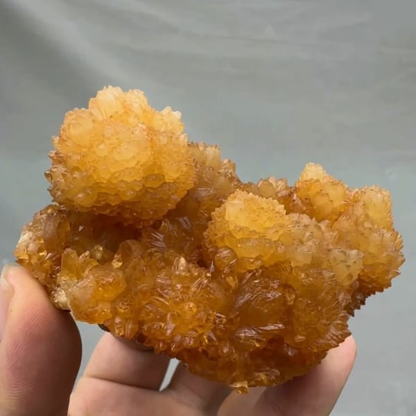 Golden-yellow botryoidal calcite balls from Guizhou, China, held in hand