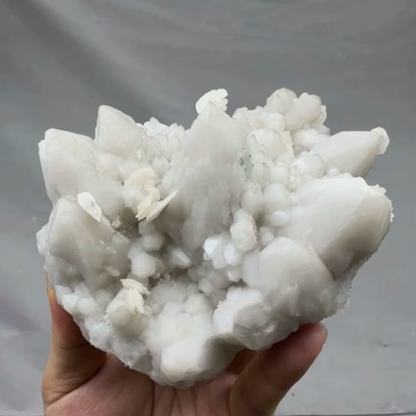 Chunky white quartz cluster with calcite from Xianghualing, Hunan, China, held in hand