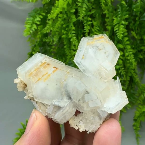 Stacked hexagonal calcite plates with orange growth lines from Fujian, China, held in hand