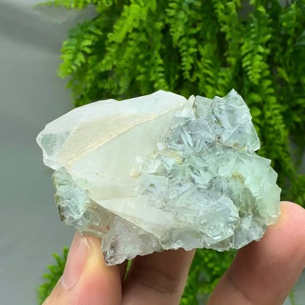 Transparent green fluorite octahedra with white calcite blade from Fujian, China, held in hand