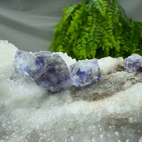 Deep purple dodecahedral fluorite on white quartz plate from Fujian, China, close-up of the crystal faces