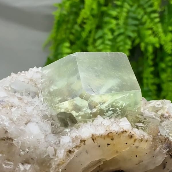 Glassy green fluorite dodecahedron on quartz druse from Fujian, China, close-up of the crystal faces