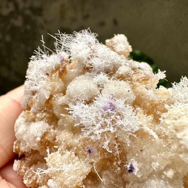 Fuzzy white aragonite tufts over yttrofluorite and gypsum from Guizhou, China, close-up of the crystal faces