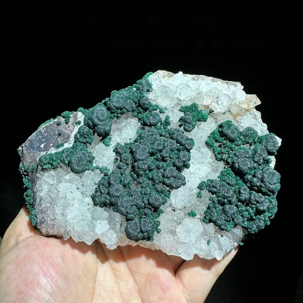 Green malachite islands on white quartz plate from Laos, held in hand
