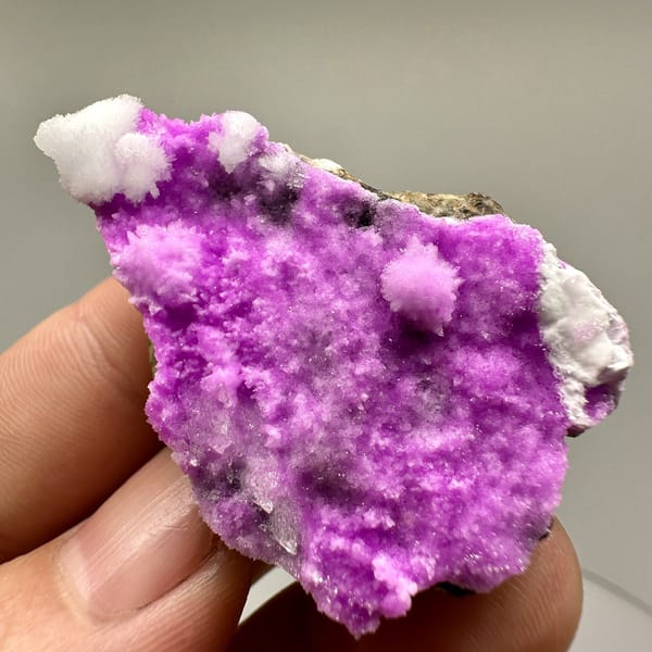 Vivid magenta aragonite with white aragonite tufts from Yunnan, China, detail of the matrix contact