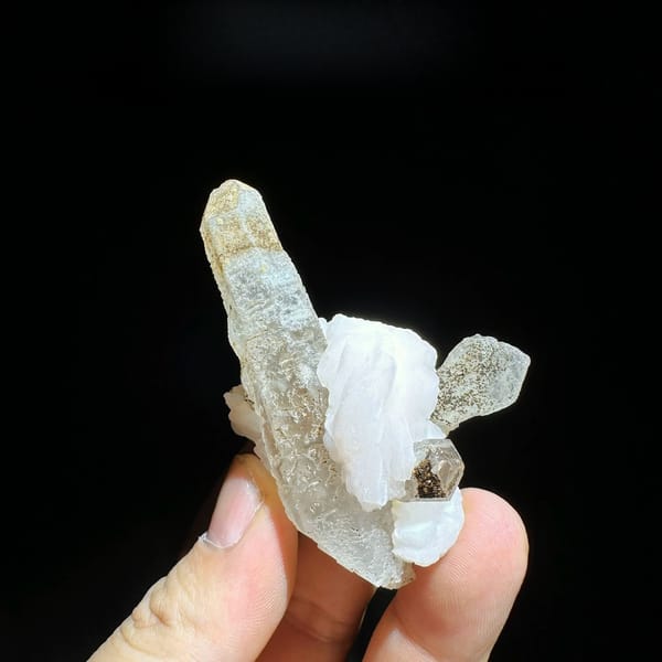Slender frosted quartz prism with white calcite blade from Inner Mongolia, China, held in hand