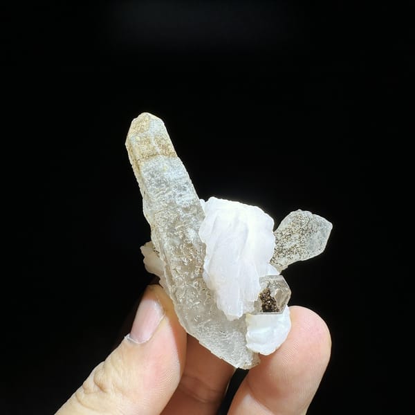Slender frosted quartz prism with white calcite blade from Inner Mongolia, China, detail of the matrix contact