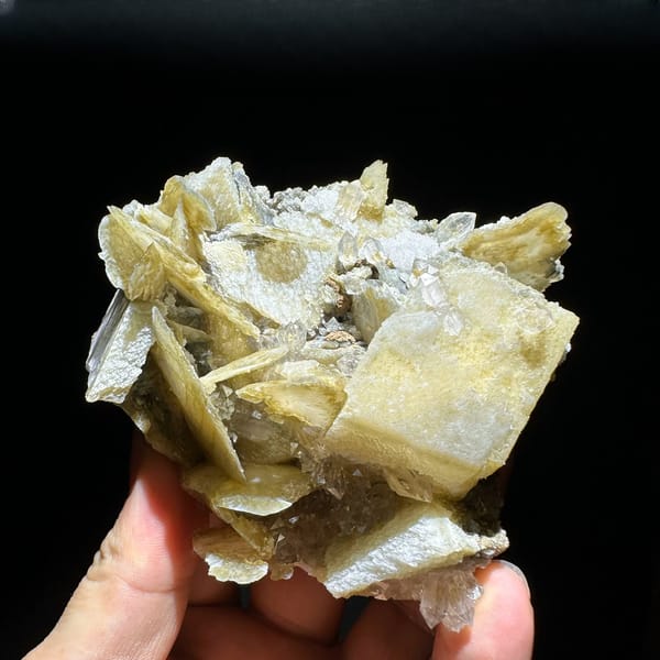 Phantom scepter quartz among tan platy calcite from Inner Mongolia, China, held in hand