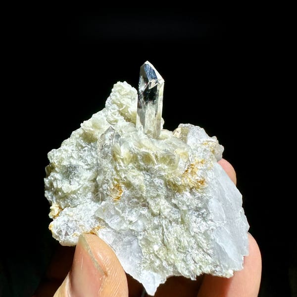 Clear quartz point standing in pearly muscovite from Xuebaoding, Sichuan, China, held in hand