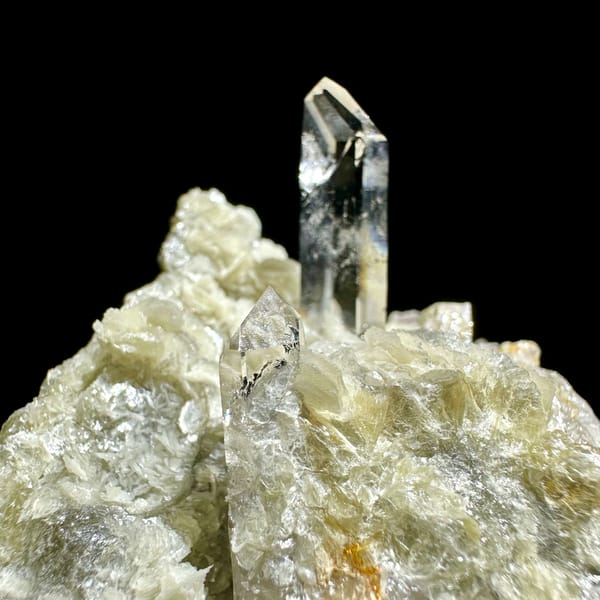 Clear quartz point standing in pearly muscovite from Xuebaoding, Sichuan, China, close-up of the crystal faces
