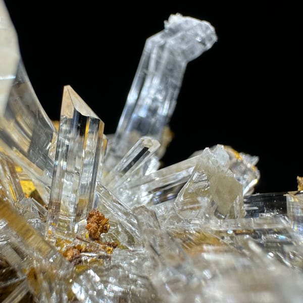 Ultra-clear gypsum blades on ochre-yellow rock from Guizhou, China, close-up of the crystal faces