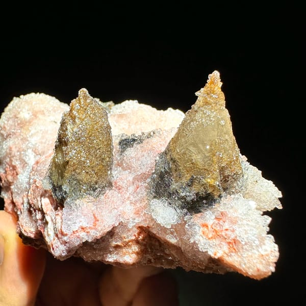 Coffee-brown calcite spikes on pink gypsum from Guizhou, China, close-up of the crystal faces