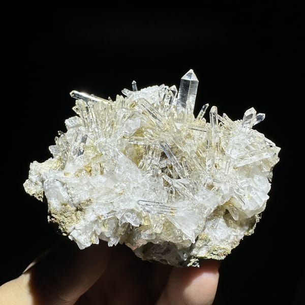 Dense cluster of transparent quartz needles from Hunan, China, detail of the matrix contact