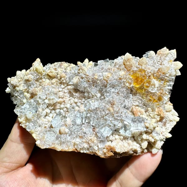 Ice-clear fluorite cubes on quartz plate from Guizhou, China, held in hand
