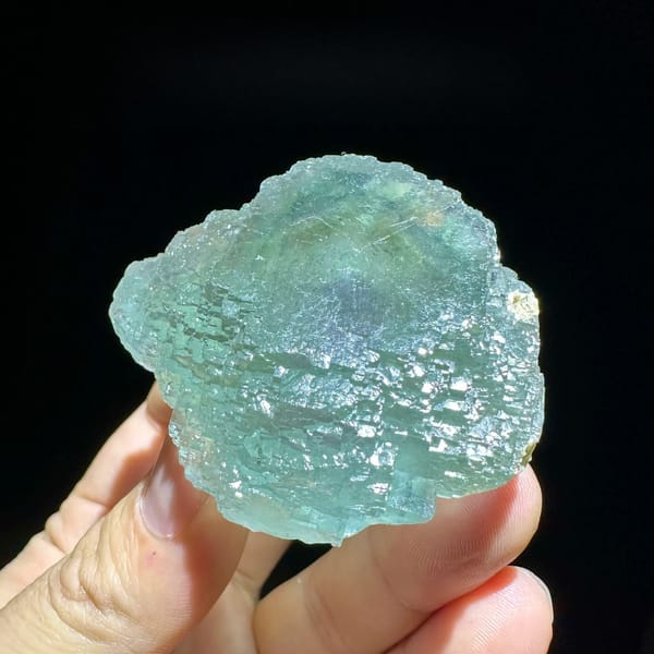 Large sea-green fluorite crystal with purple core from Guangxi, China, held in hand