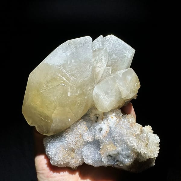 Huge golden calcite crystal on white quartz druse from Fujian, China, held in hand