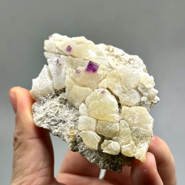 Cream fluorite octahedra with purple-red fluorite on quartz from Zhejiang, China, close-up of the crystal faces