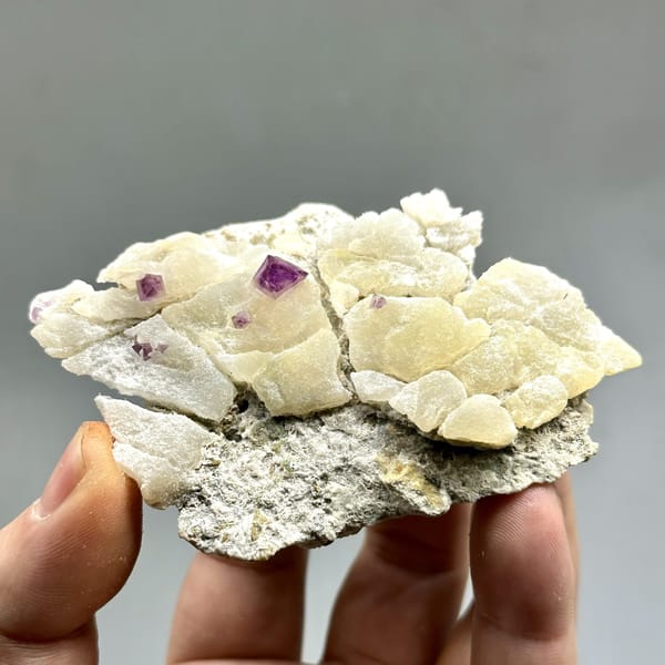 Cream fluorite octahedra with purple-red fluorite on quartz from Zhejiang, China, detail of the matrix contact