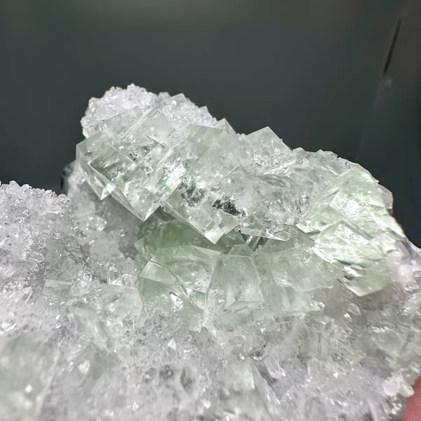 Glassy green fluorite under white quartz frosting from Zhejiang, China, close-up of the crystal faces