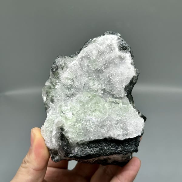 Glassy green fluorite under white quartz frosting from Zhejiang, China, detail of the matrix contact