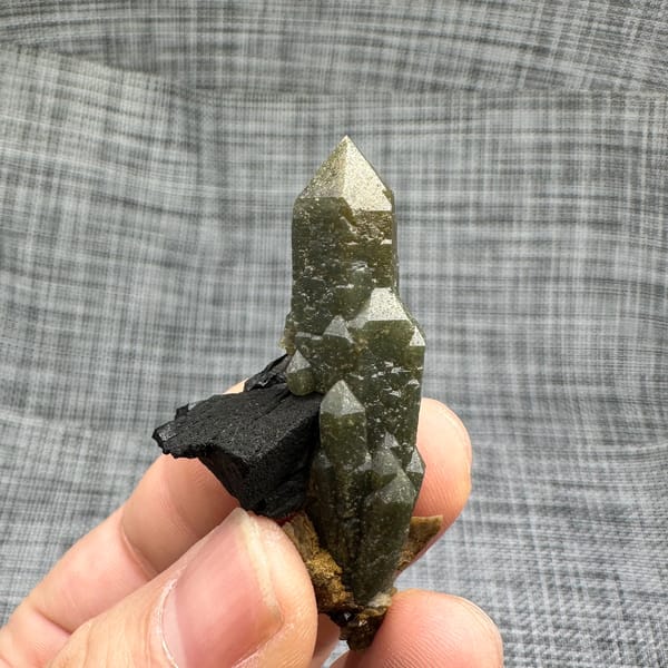 Green chlorite-coated quartz point on black matrix from Inner Mongolia, China, close-up of the crystal faces
