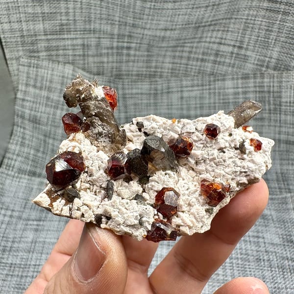 Large orange-red garnets and smoky quartz on cream feldspar from Yunxiao, Fujian, China, close-up of the crystal faces