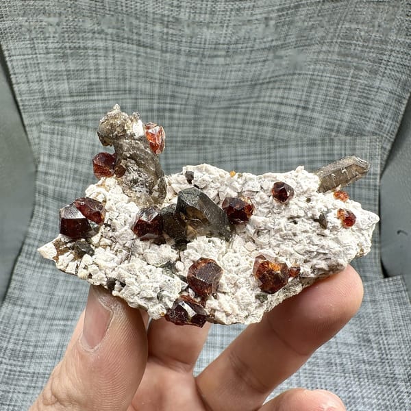 Large orange-red garnets and smoky quartz on cream feldspar from Yunxiao, Fujian, China, detail of the matrix contact