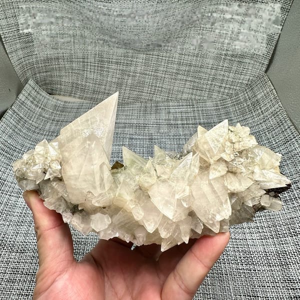 Arc of sharp cream calcite spikes with tall blade from Fujian, China, held in hand