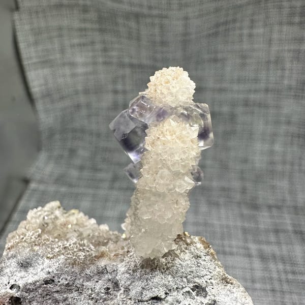 Blue-green fluorite dodecahedron on white quartz stalk from Fujian, China, close-up of the crystal faces
