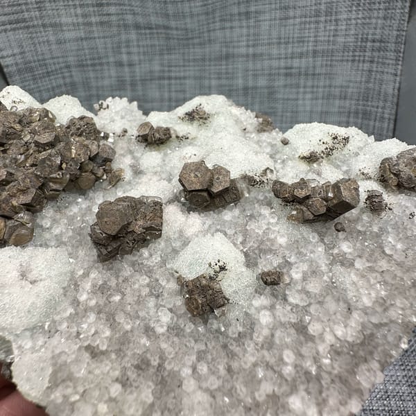 Chocolate-brown calcite clusters on white sugar fluorite plate from Fujian, China, close-up of the crystal faces