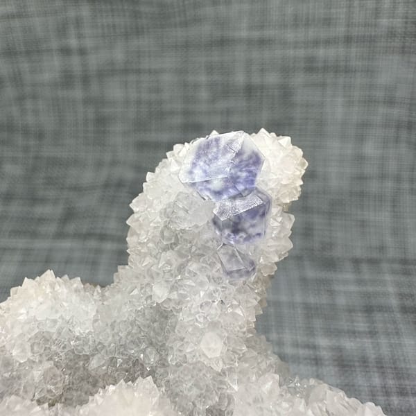 Purple-blue fluorite dodecahedron on white quartz mound from Fujian, China, reverse side