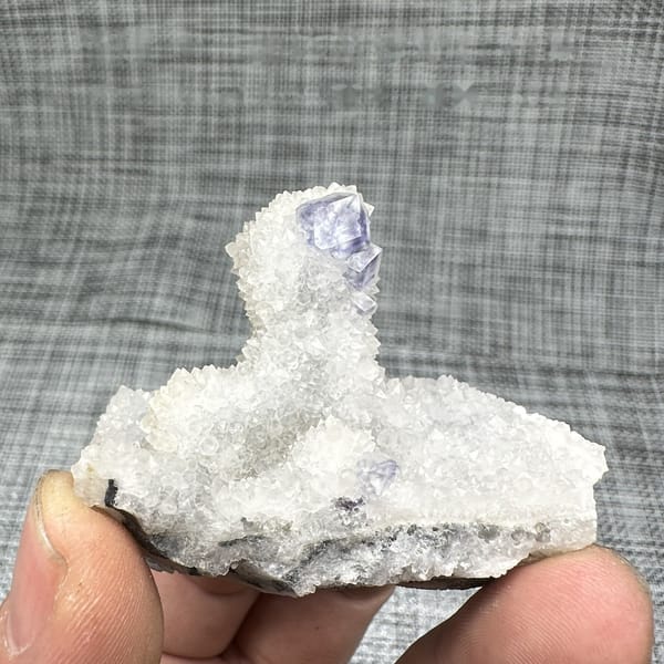 Purple-blue fluorite dodecahedron on white quartz mound from Fujian, China, detail of the matrix contact