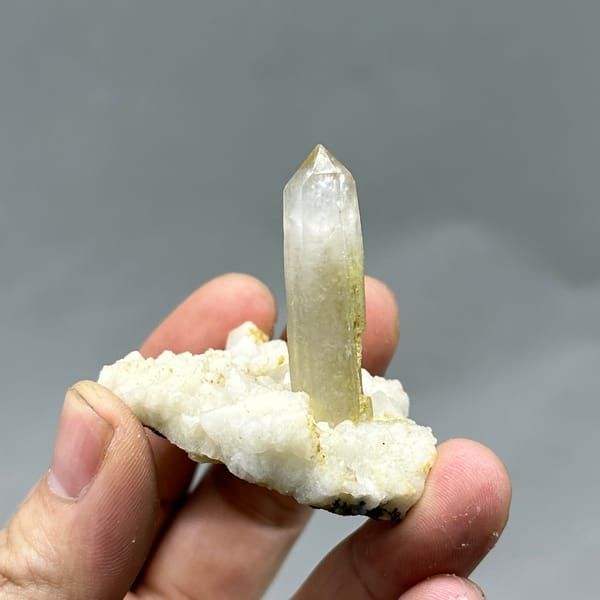 Gradient quartz point standing on white feldspar from Yunxiao, Fujian, China, detail of the matrix contact