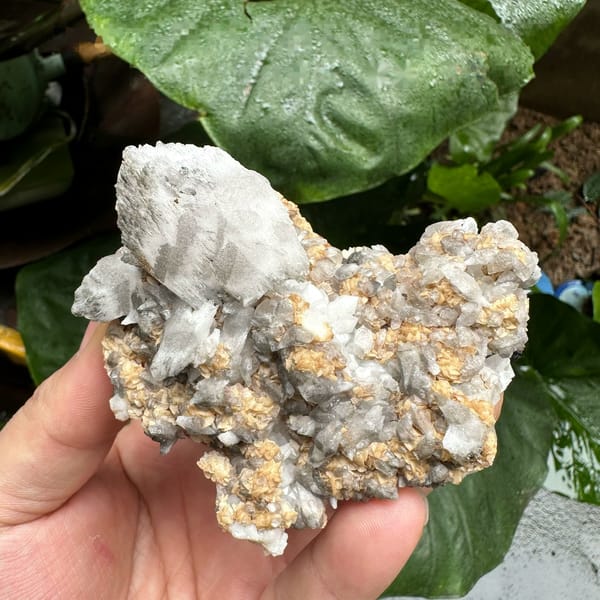 Shield-shaped calcite crystal on quartz and dolomite from Inner Mongolia, China, held in hand