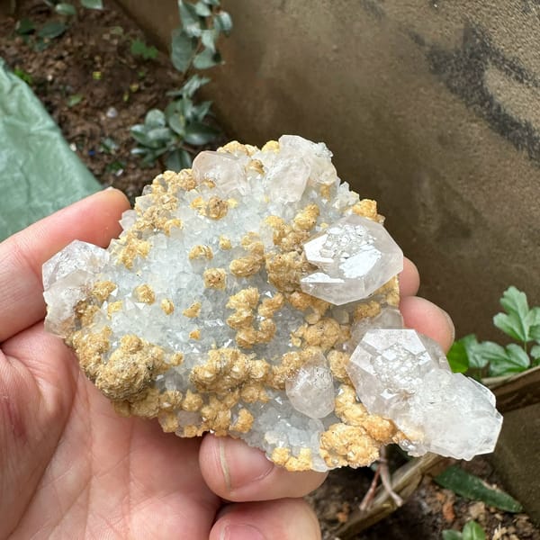 Pale pink calcite with tan dolomite crusts from Jiangxi, China, held in hand