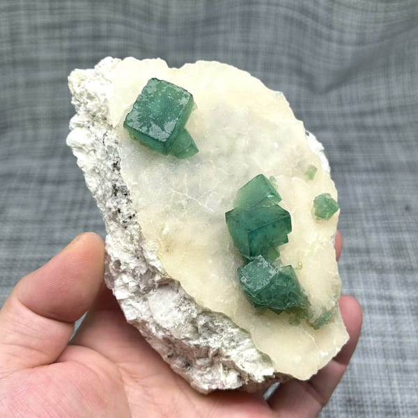 Emerald-green daylight fluorite cubes on cream quartz plate from Madagascar, close-up of the crystal faces