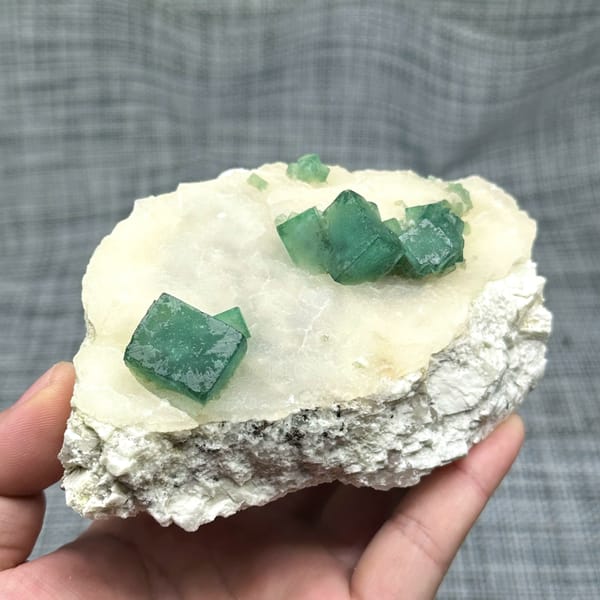 Emerald-green daylight fluorite cubes on cream quartz plate from Madagascar, reverse side