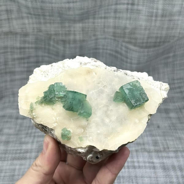 Emerald-green daylight fluorite cubes on cream quartz plate from Madagascar, detail of the matrix contact